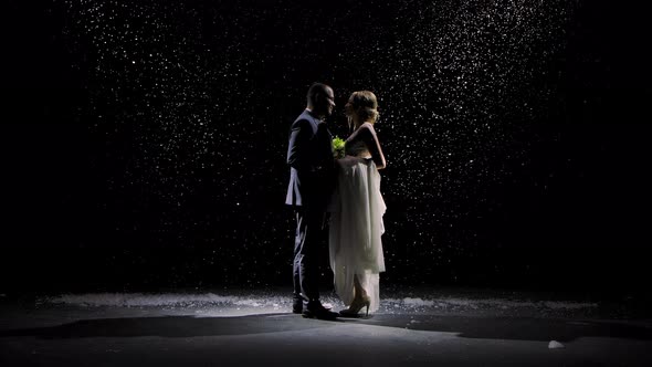 Happy Couple in Love Approach Each Other and Kiss Against the Background of Falling Snow. Man in a