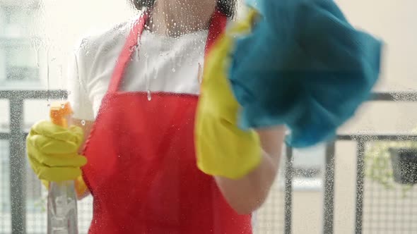 Female Hands in Yellow Gloves Cleaning Window Pane with Rag and Spray Detergent