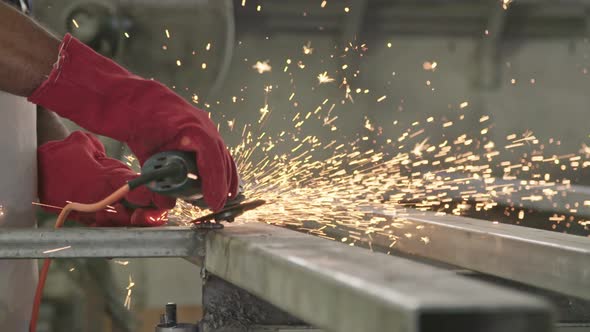 Slow motion of a worker using metal grinder with sparks flying at a metal shop