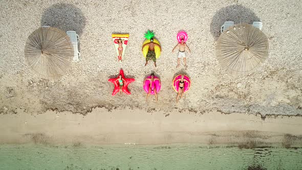 Aerial view of people lying on big inflatable mattresses on beach.