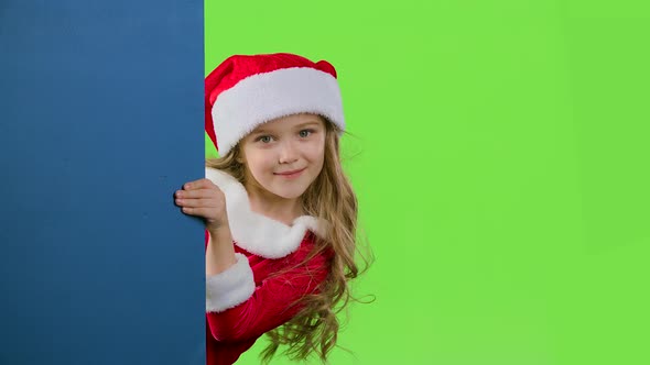 Kid Girl Peeking Out From Behind the Blue Board. Green Screen. Slow Motion