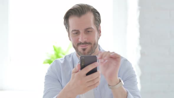 Young Man Celebrating Success on Smartphone