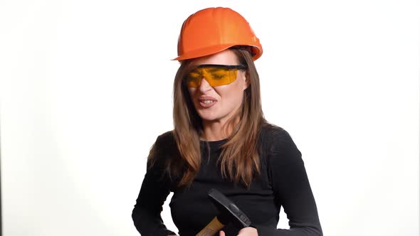 beautiful woman in orange eyeglasses and helmet is holding a hammer in her hands