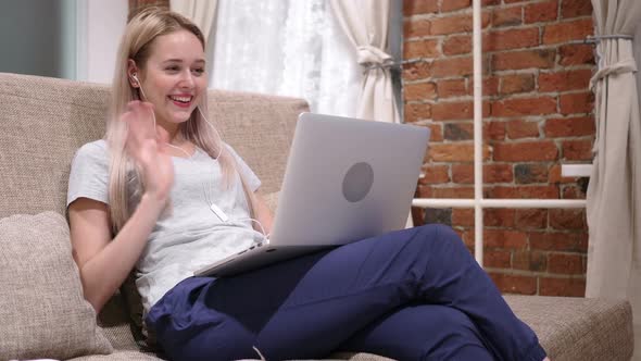 Woman Doing Video Chat on Laptop Sitting on Sofa at Home