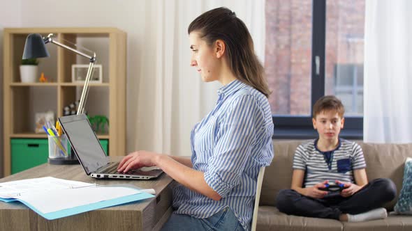 Mother Working at Home and Son Playing Video Game