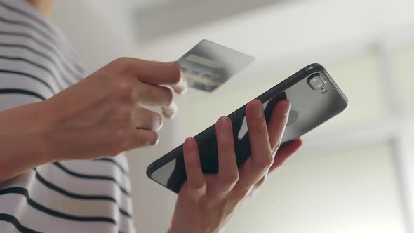 Woman holding smartphone and mock up credit card with paying for shopping online.