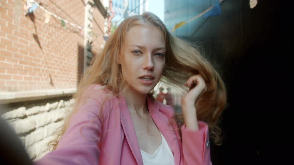 Portrait of Cute Young Blonde Taking Selfie Posing with Funny Faces Looking at Camera Outdoors