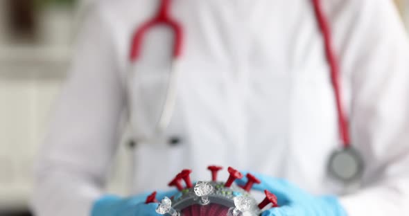 The Doctor is Holding a Plastic Model of the Coronovirus