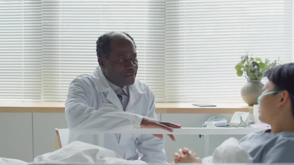 Doctor Visiting Asian Female Patient in Hospital Ward