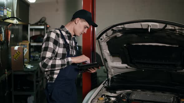Mechanic Inspects the Car Undercarriage Way with a Digital Tablet
