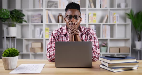 Thoughtful Young african man working on laptop at home