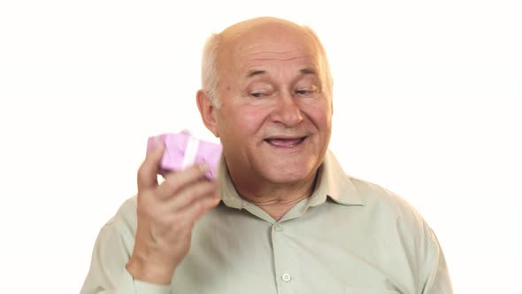Happy Grandpa Smiling Listening To a Gift Box Guessing What Is Inside
