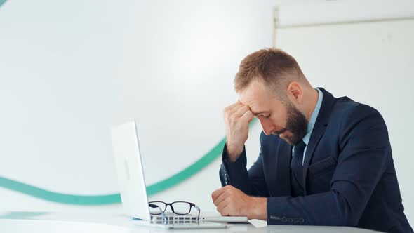 Sad and Tired Businessman Sitting in White Office