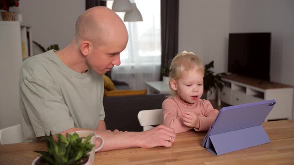 A Child with Cochlear Implants Plays with a Tablet Computer with His Father