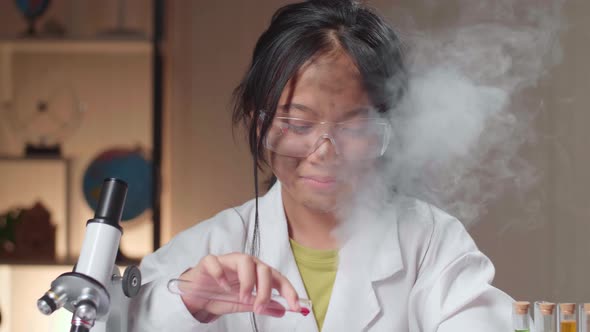 Young Asian Scientist Girl With Dirty Face Mixing Chemical Liquids In Flasks