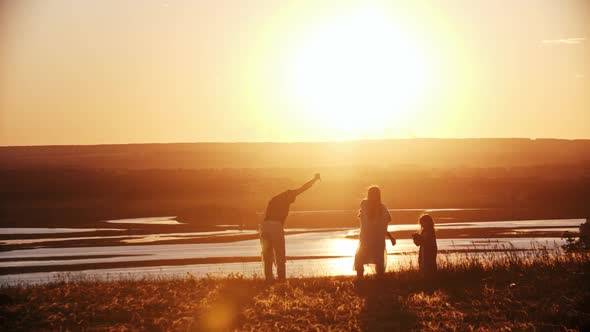 Young Family Playing with a Kite on the Field While the Sunset