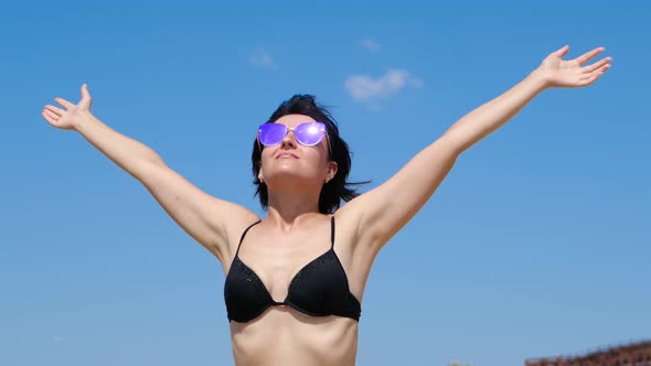 Young Brunette Girl with Raised Hands Towards a Blue Sky on a Sunny Day