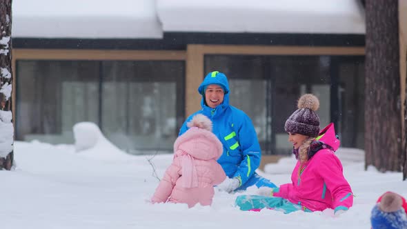 Joyful Parents Throw Snowballs and Children Play on Snow