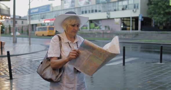 Senior Female Tourist Exploring Town with a Map in Hands. Looking for the Route