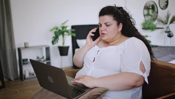 Overweight Lady Employee Talks on Phone Working on Laptop