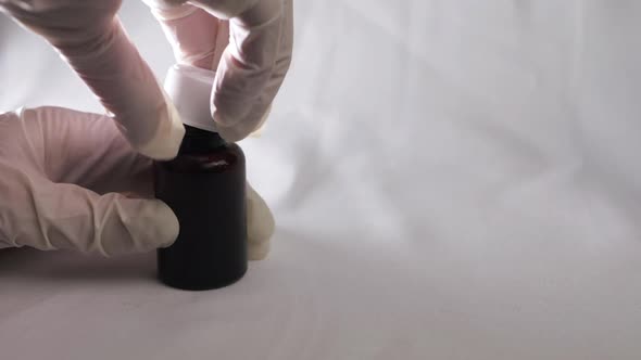 Putting cap on bottle of medicine with white gloves close up shot