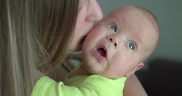 Portrait of Happy Mother Kisses Her Newborn Baby on Hands