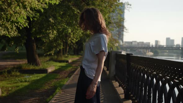 Happy Woman is Strolling on City Embankment at Sunny Summer Day Following Shot