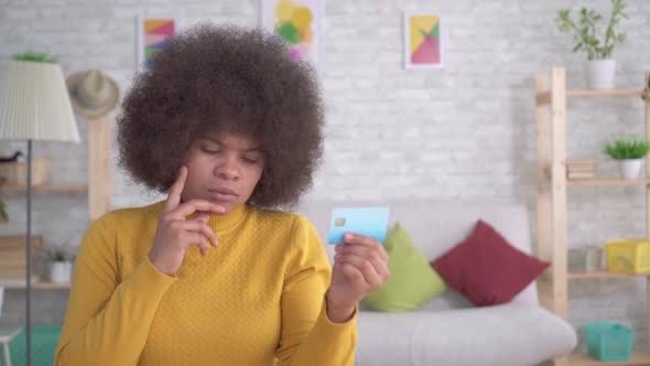 Portrait African American Woman Thoughtful and Serious Looking at the Bank Card in His Hands