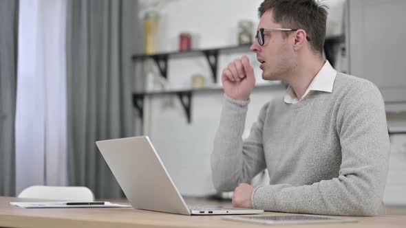 Sick Young Man Coughing While Working on Laptop