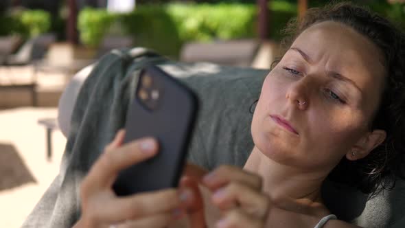 Close Up of Pensive Caucasian Woman Texting on Her Phone While Resting at the Beach