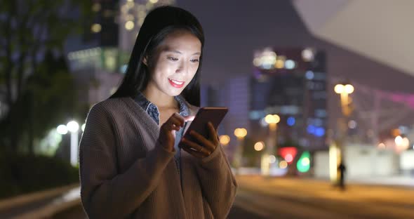 Young woman use of mobile phone in city at night