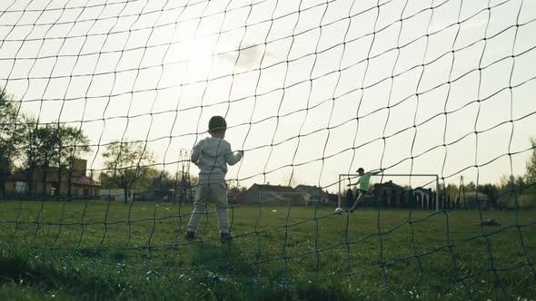 The Child Stands at the Football Goal and is Afraid of the Ball