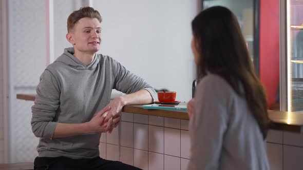 Young Positive Caucasian Boyfriend Talking with Girlfriend in Student Canteen Sitting at Counter