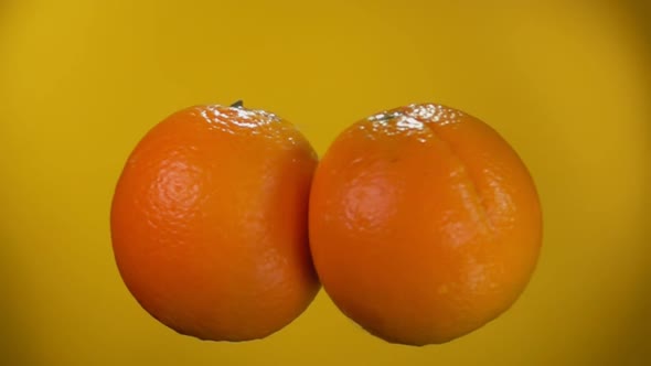 Two Oranges Are Colliding with Each Other on the Yellow Background