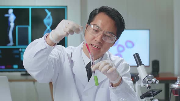 Young Asian Male Research Scientist Holding Glass Test Tube And Speaking To The Camera