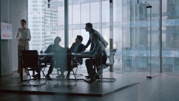 Mature businesswoman giving presentation to male colleagues in modern office