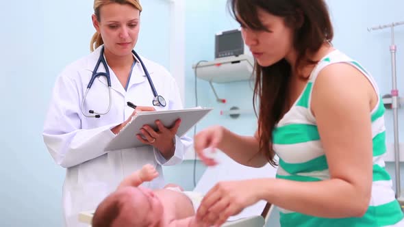 Woman and doctor with a baby on a changing table