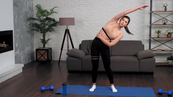 Young Fit Woman in Sportswear Doing Warmup Before Workout on Yoga Mat at Home