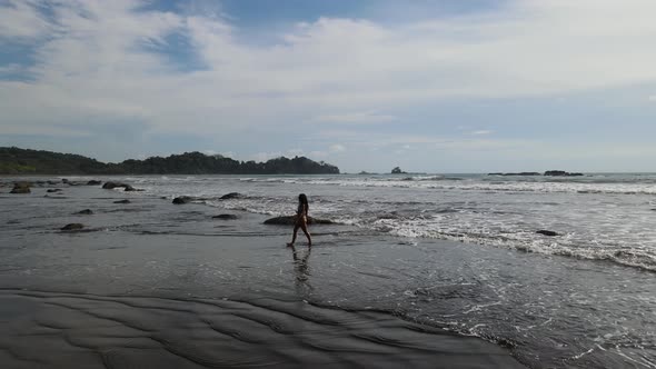 Wide establishing shot of a lady walking on a beach in Costa Rica. Summer holiday travel footage