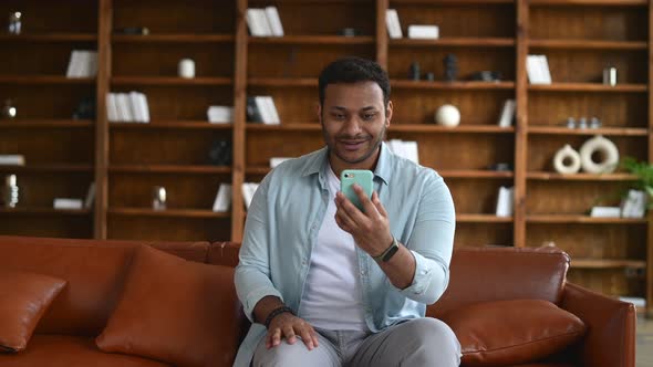 Serious Focused Indian Man in Casual Wear Using Smartphone App for Video Call