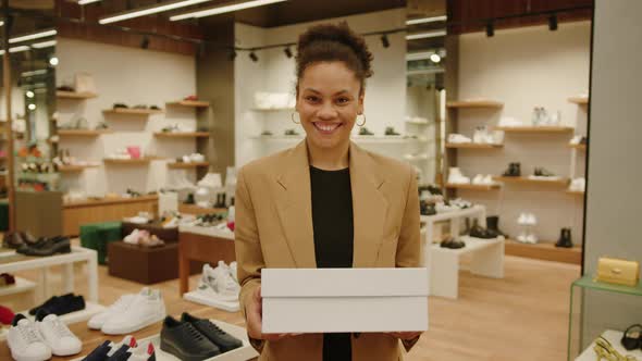 A Happy Strong AfricanAmerican Woman Holds a Box of Shoes in Her Hands