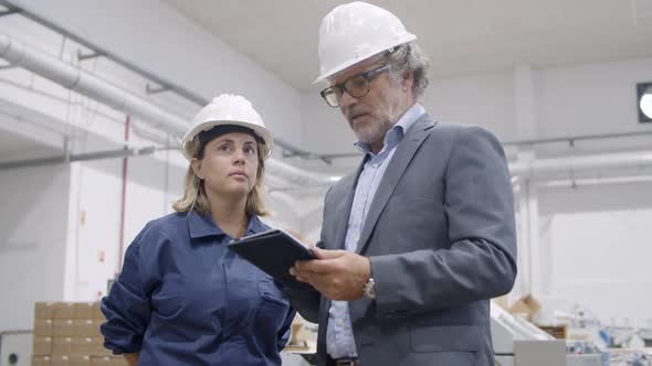 Older Engineer Using Tablet and Showing Machinery Work Process