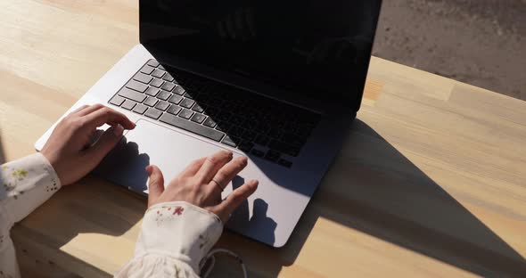 Female user hands typing on laptop keyboard.