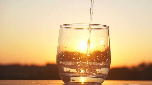 Mineral Water Is Being Poured on the Sunset Background