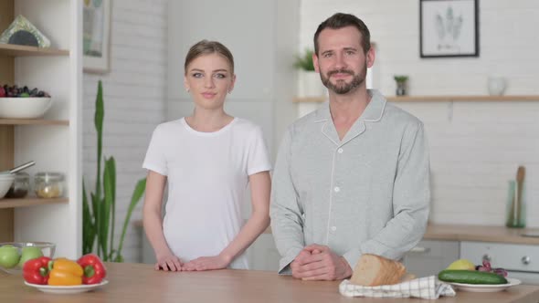 Young Woman and Man Smiling at Camera in Kitchen