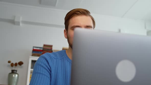 Young male using laptop, studying online, working from home, typing on laptop