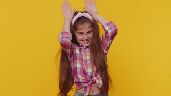 Lovely Funny Comical Child Girl Kid Smiling Friendly and Doing Bunny Ears Gesture on Head Fooling