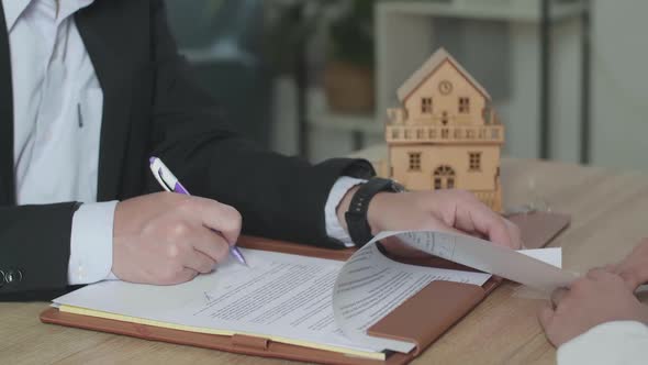 Close Up Of Real Estate Agent With A Woman Signing On House Purchase Contract Paper