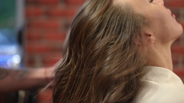 Side View Combing Long Curly Brunette Hair in Beauty Salon Indoors