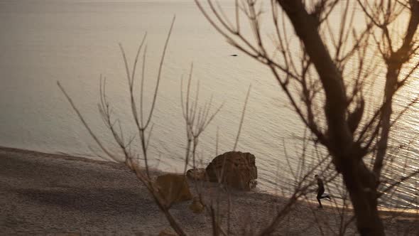 Footage of Silhouette of Male Quickly Running Along Seashore in Slowmotion